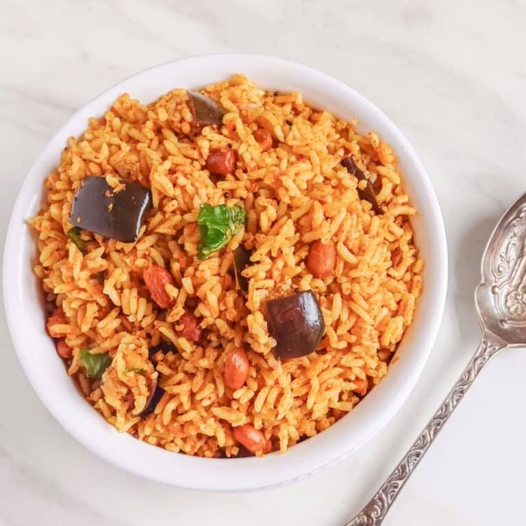 white bowl filled with vangibath placed on marble along with a spoon.