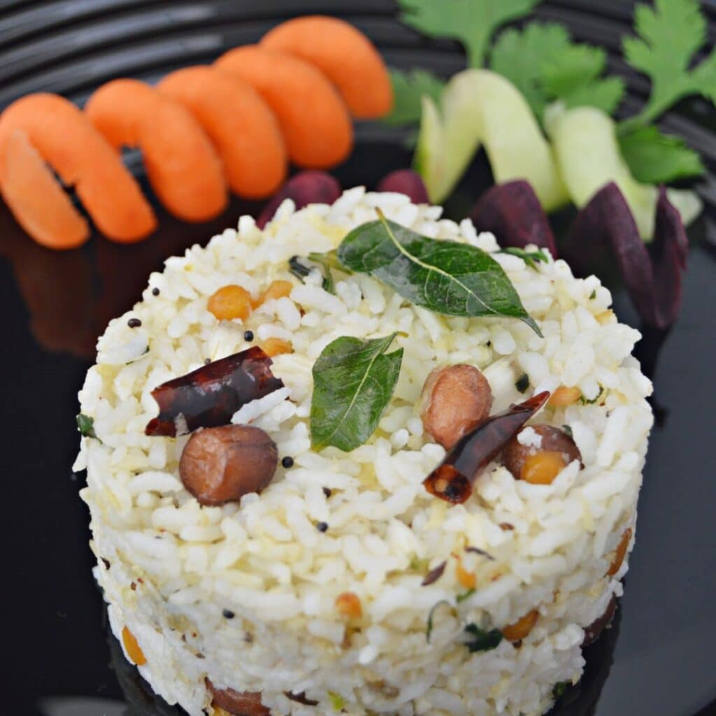 coconut rice placed on a black plate with carrot and cucumber .