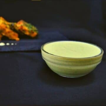 close up shot of mint sauce in a bowl placed on a black background.