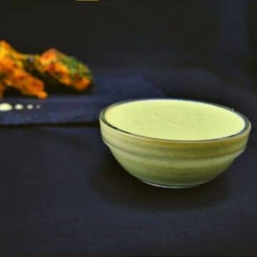 close up shot of mint sauce in a bowl placed on a black background.