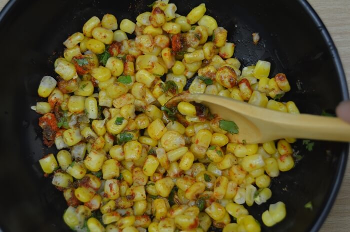 mixing masala corn with spoon.