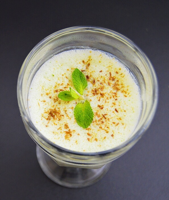 masala lassi in a glass with mint sprig on top.