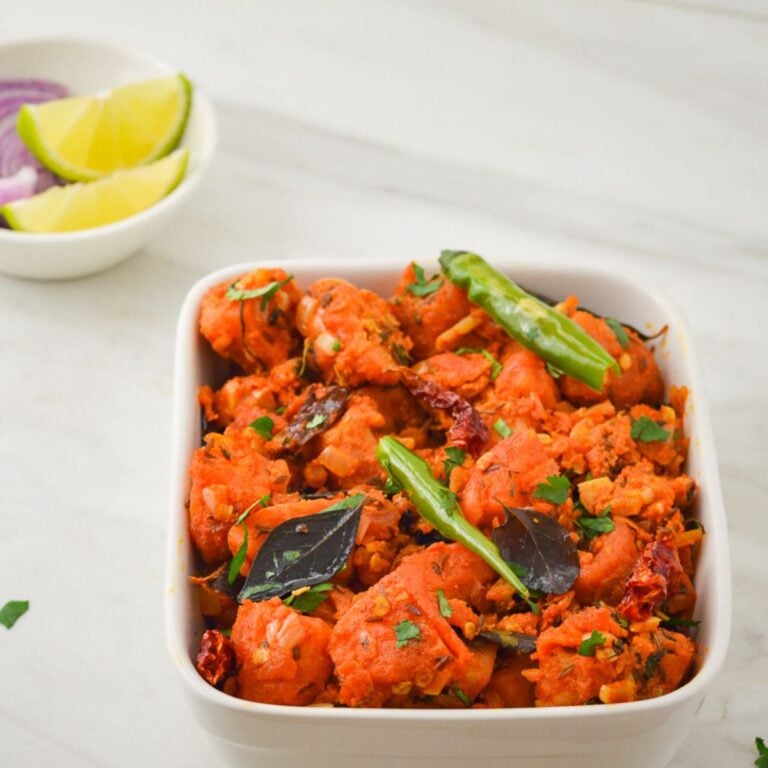 white bowl of potato 65 placed on marble along with a bowl of lemon wedges and onion slices.