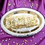 a silver plate of 7 cup burfis placed on a purple cloth.