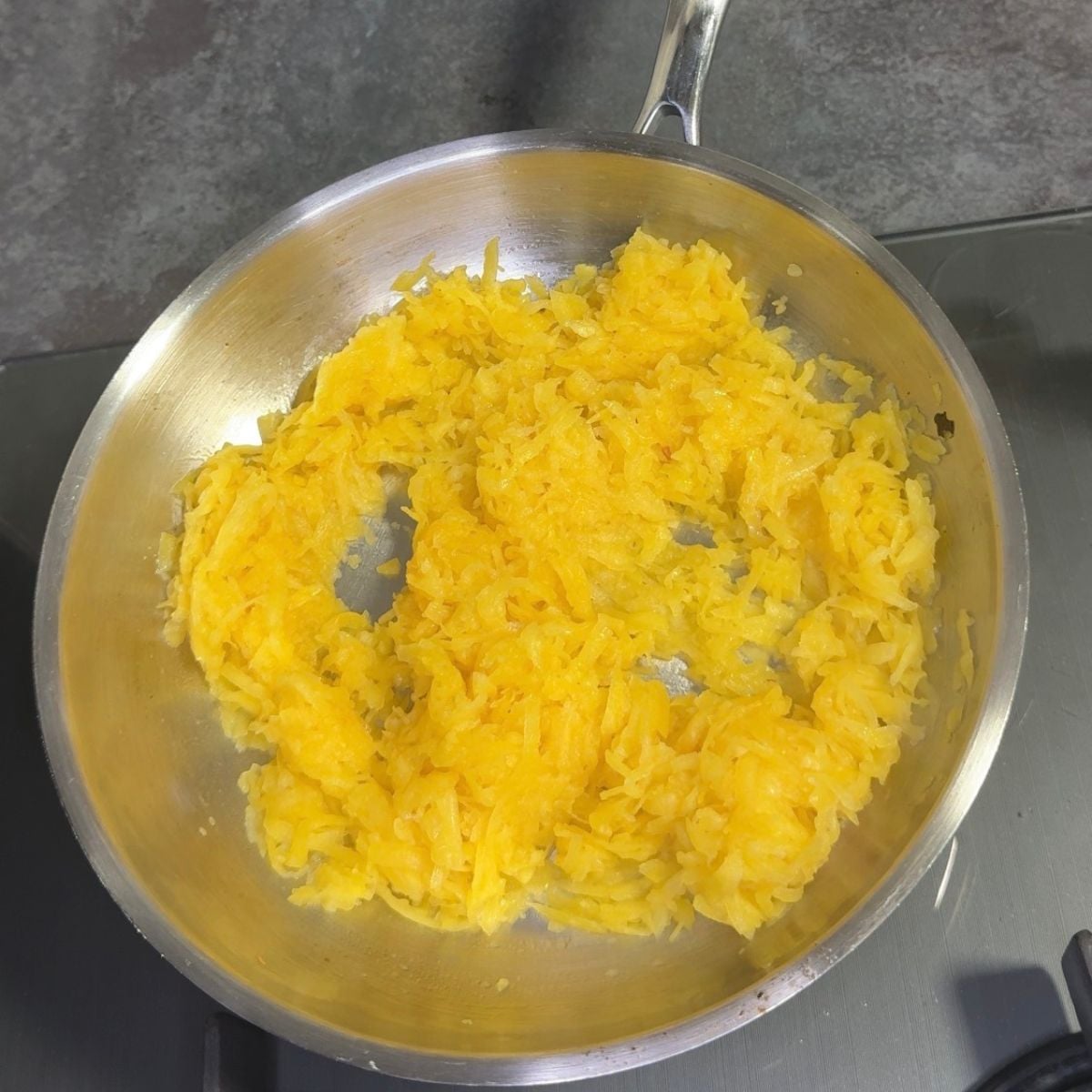frying grated pumpkin in steel pan to make kaddu ka halwa.