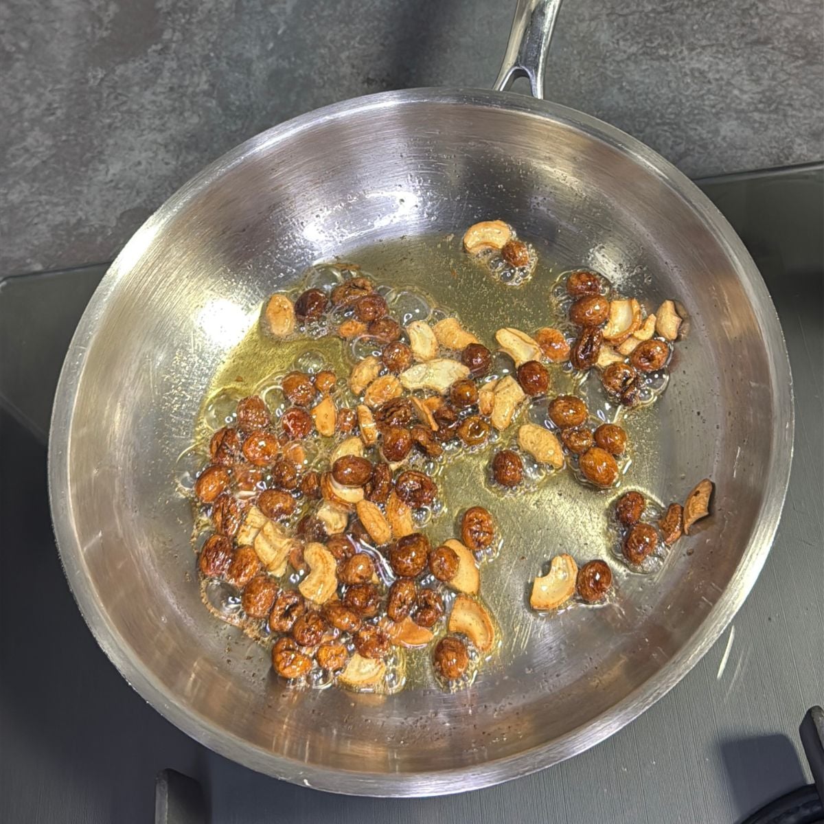 frying cashews and raisins in a steel pan.