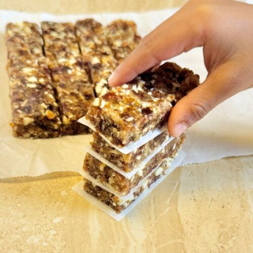 child holding top date bar from the stack of no bake date bars placed on granite.