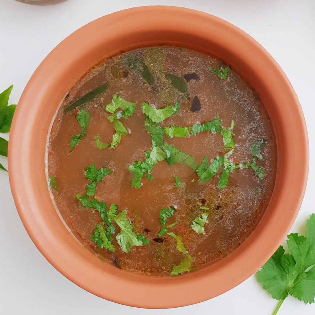 dal rasam in brown bowl placed on white table