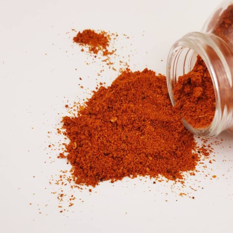 Jar of authentic bisi bele bath powder spilled over on a white table.