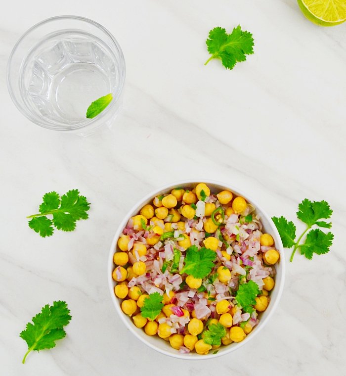 simple chickpea salad in a white bowl with glass of water
