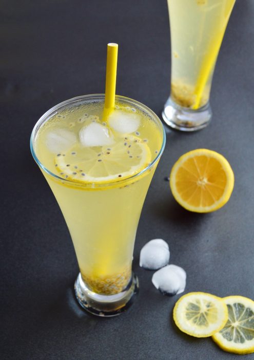 simple lemonade with basil seeds in a glass with yellow straw.