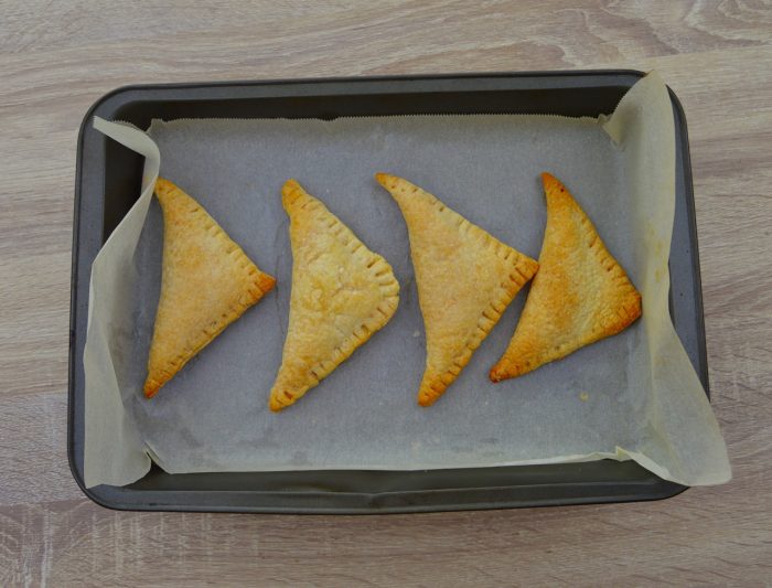 4 baked curry puffs in baking tray.