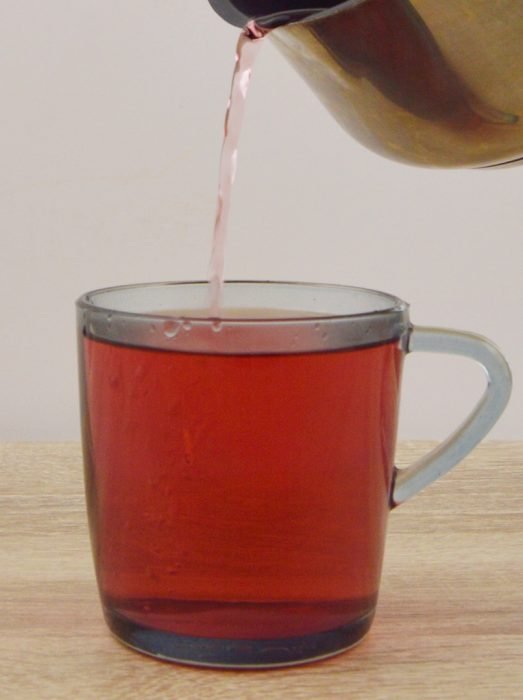 pouring hibiscus tea in a glass.