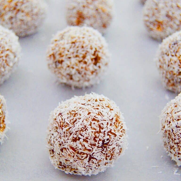 no bake coconut date balls placed on a parchment paper.