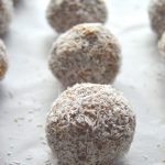 pin image of coconut date balls placed on a baking sheet with text overlay on top and bottom.