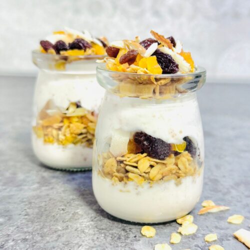 two jars of strawberry honey yogurt granola parfaits placed on a granite.