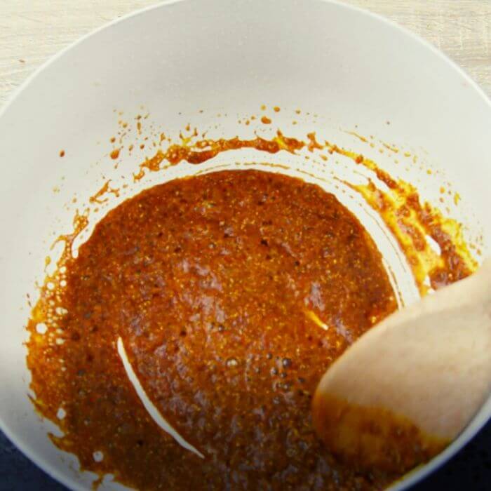 cooking dry spices in oil in a white pan.