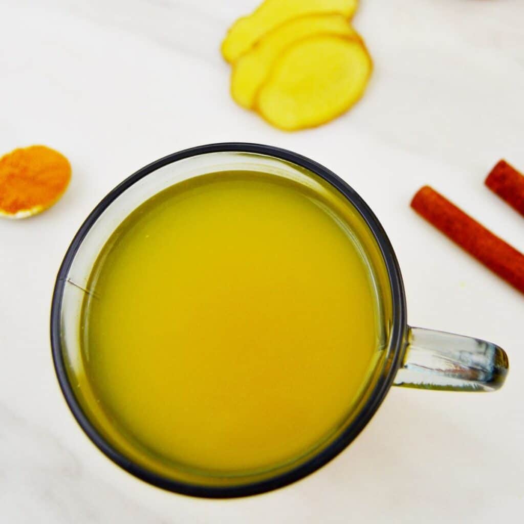 lemon ginger turmeric tea in a glass placed on the marble.