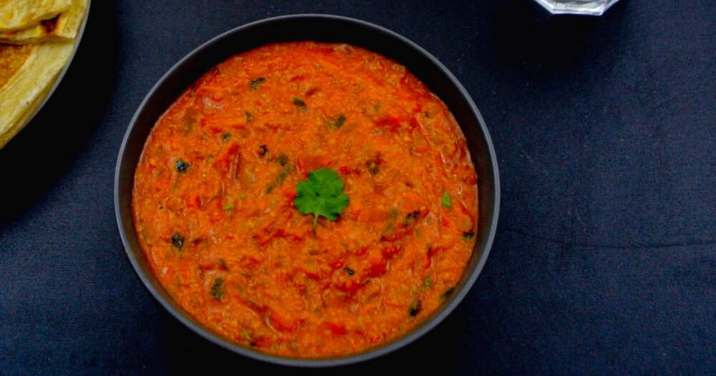 tomato kurma in a black bowl on a table.