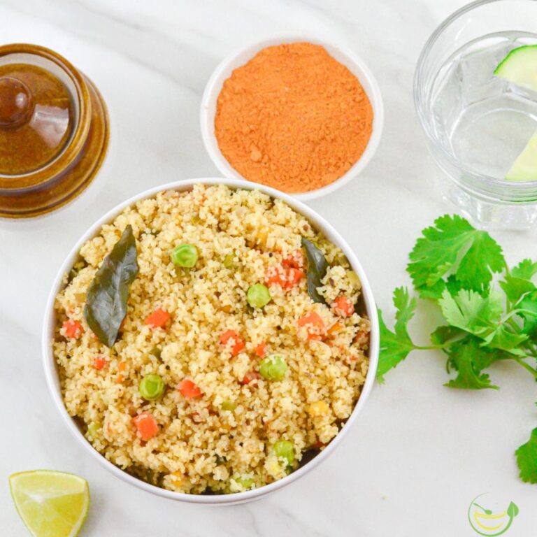 vegetable rava upma in a white bowl on a white table with a coriander leaves on side.