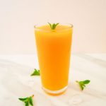 pin image of mango lemonade in a glass with mint sprig on top on a marble with text saying frozen mango lemonade.