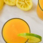 pin image of mango lemonade in a glass with lemon slice on rim on a marble with text saying mango lemonade.