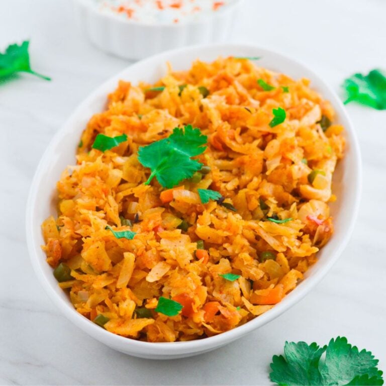 kothu parotta in a white bowl on marblw with a bowl of raita behind it.