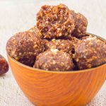 pinterest image showing brown bowl of chocolate date energy balls placed on a granite with pink text overlay on top and bottom.