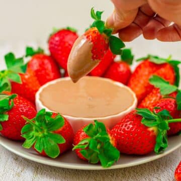 strawberry platter with a white bowl of chocolate dip in the middle placed on a granite background.