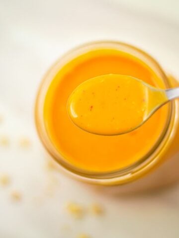 holding a spoon of peanut dressing above the dressing bottle.
