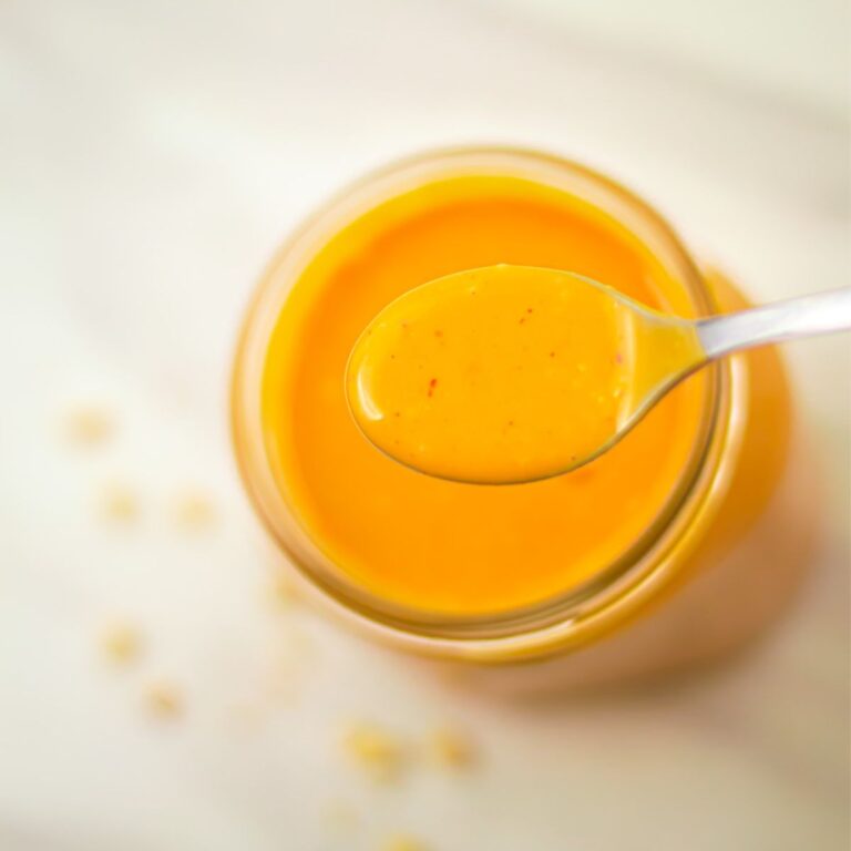 holding a spoon of peanut dressing above the dressing bottle.