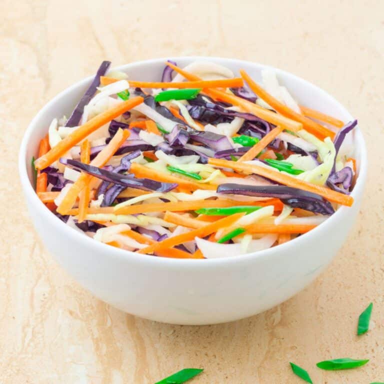 vegan coleslaw in a white bowl placed on a tile.