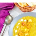 pin image of a yellow curry topped with fried paneer in a grey bowl with a text overlay on top.