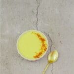 pin image of of custard in a bowl placed on a tile along with a spoon and a text overlay on top and bottom.