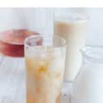 pin image of iced london fog tea latte in a high ball glass placed on a table with text overlay on top.