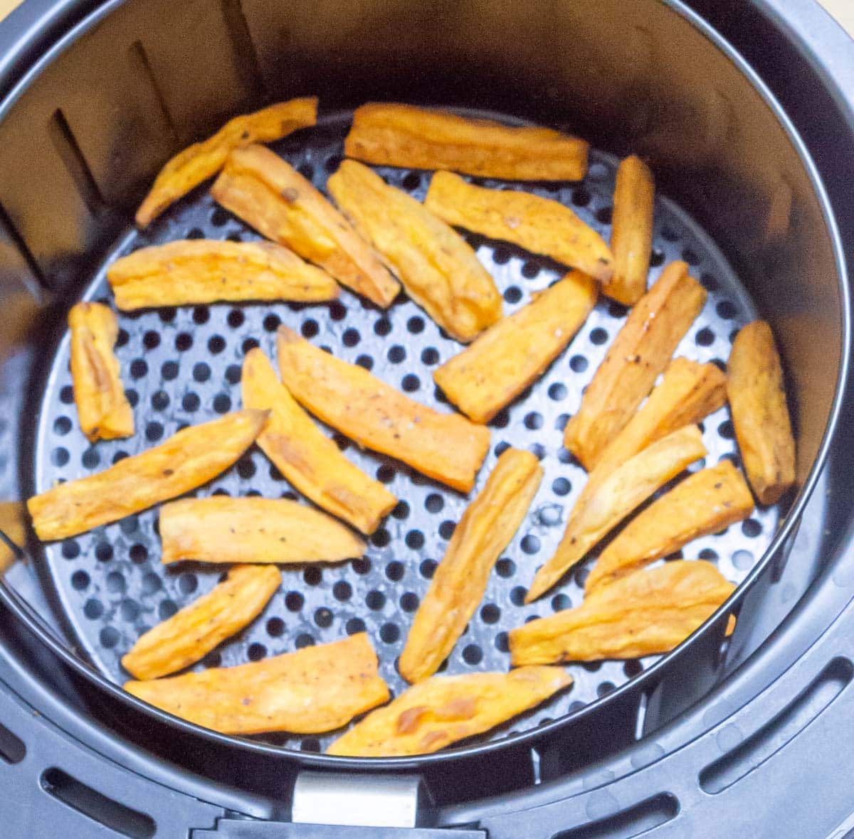 baked sweet potato wedges in air fryer basket.