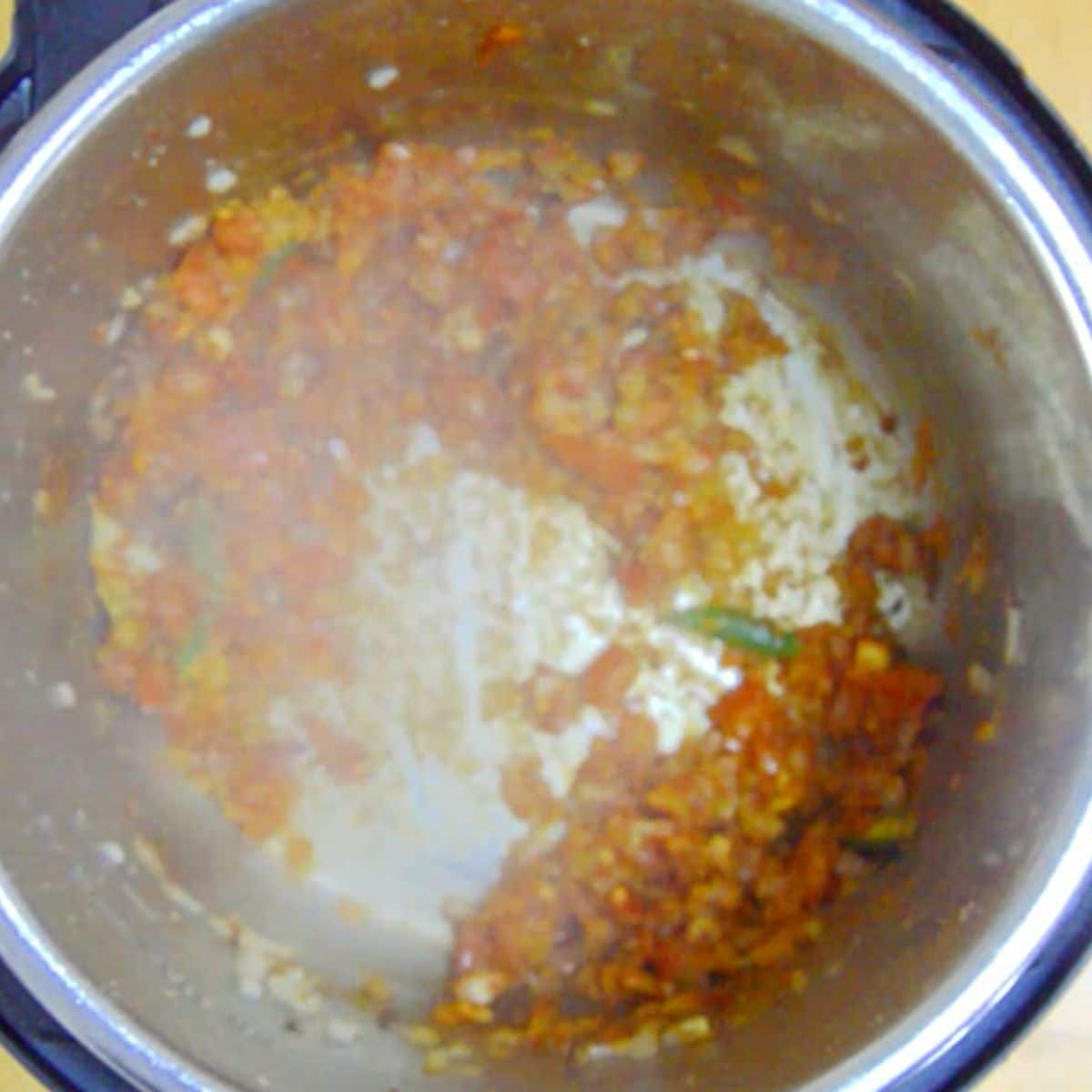 onion tomato masala with spices inside the steel pot of an instant pot.
