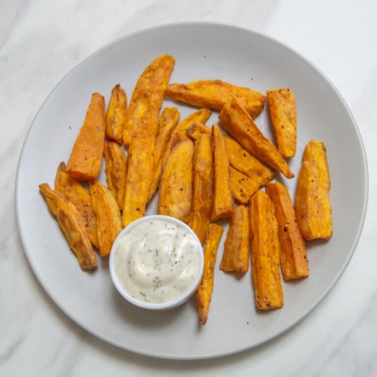sweet potato wedges in a plate along with a white dip placed on a marble.