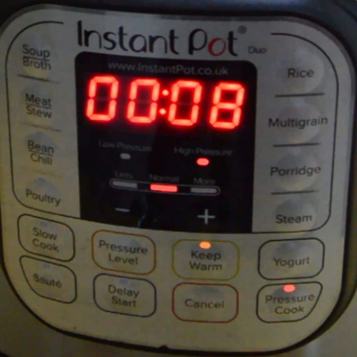 instant pot front panel with timer displaying 8 mins and red light on high pressure and warm buttons.