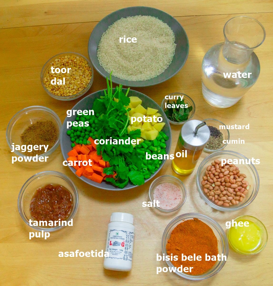 whole and dry spices, vegetables, water, rice and lentils in an individual bowls placed on a wooden table.
