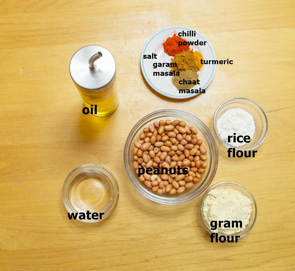 dry spices, peanuts, oil, water and flours placed on a wooden table.