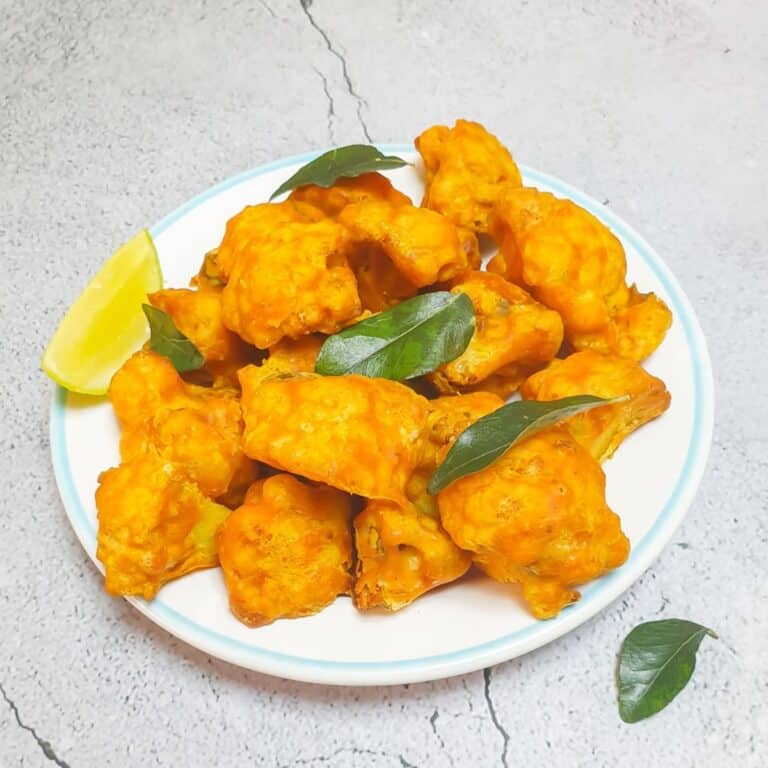 gobi 65 in a white plate with a few curry leaves placed on a tile.