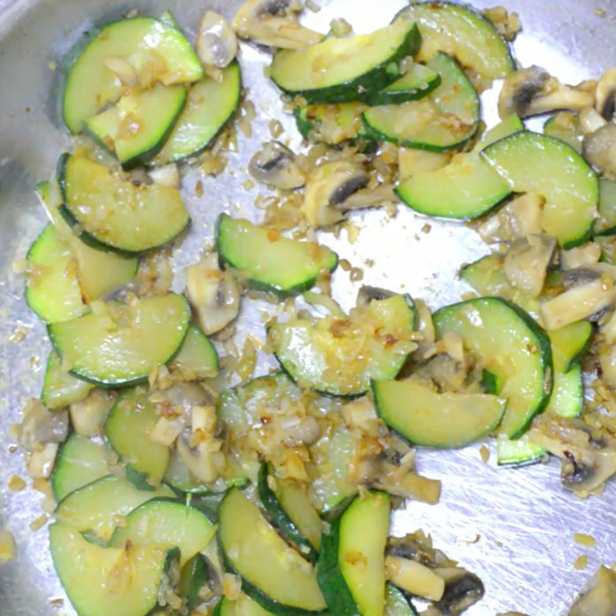 cooked zucchini and mushrooms in a steel pan.