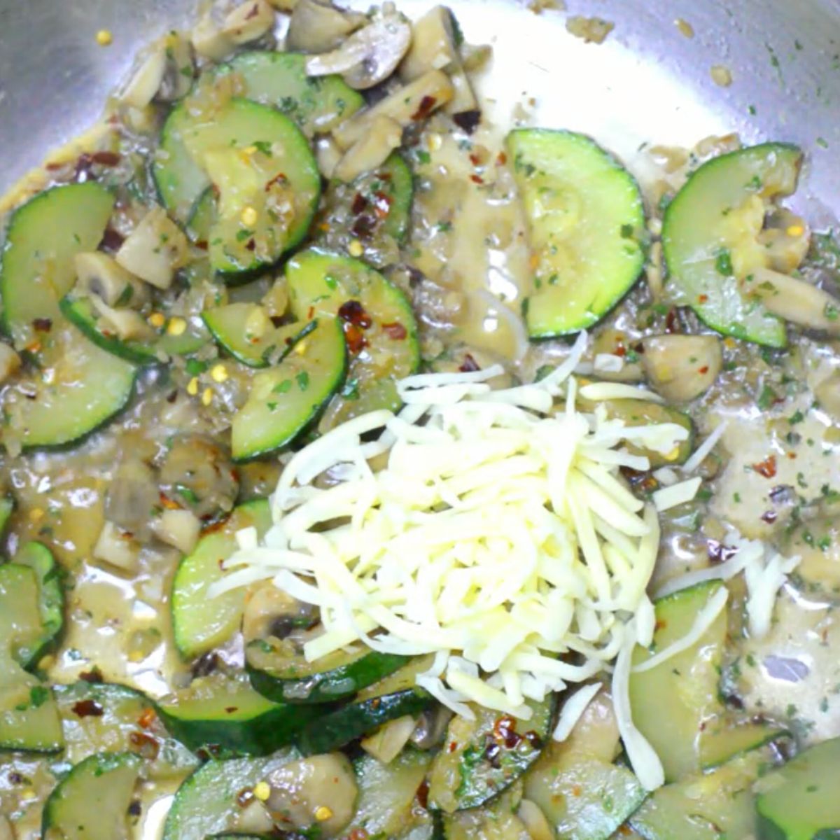 cooked zucchini mushrooms in a steel pan with cheese on top.