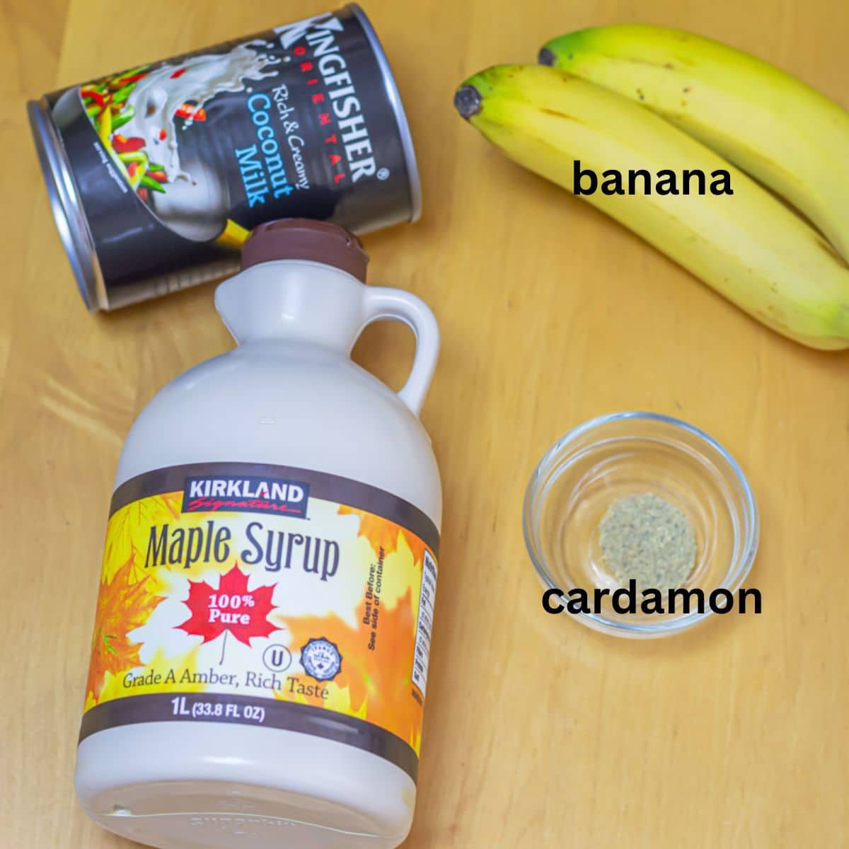 banana, coconut milk can, maple syrup and cardamom placed on a wooden table.