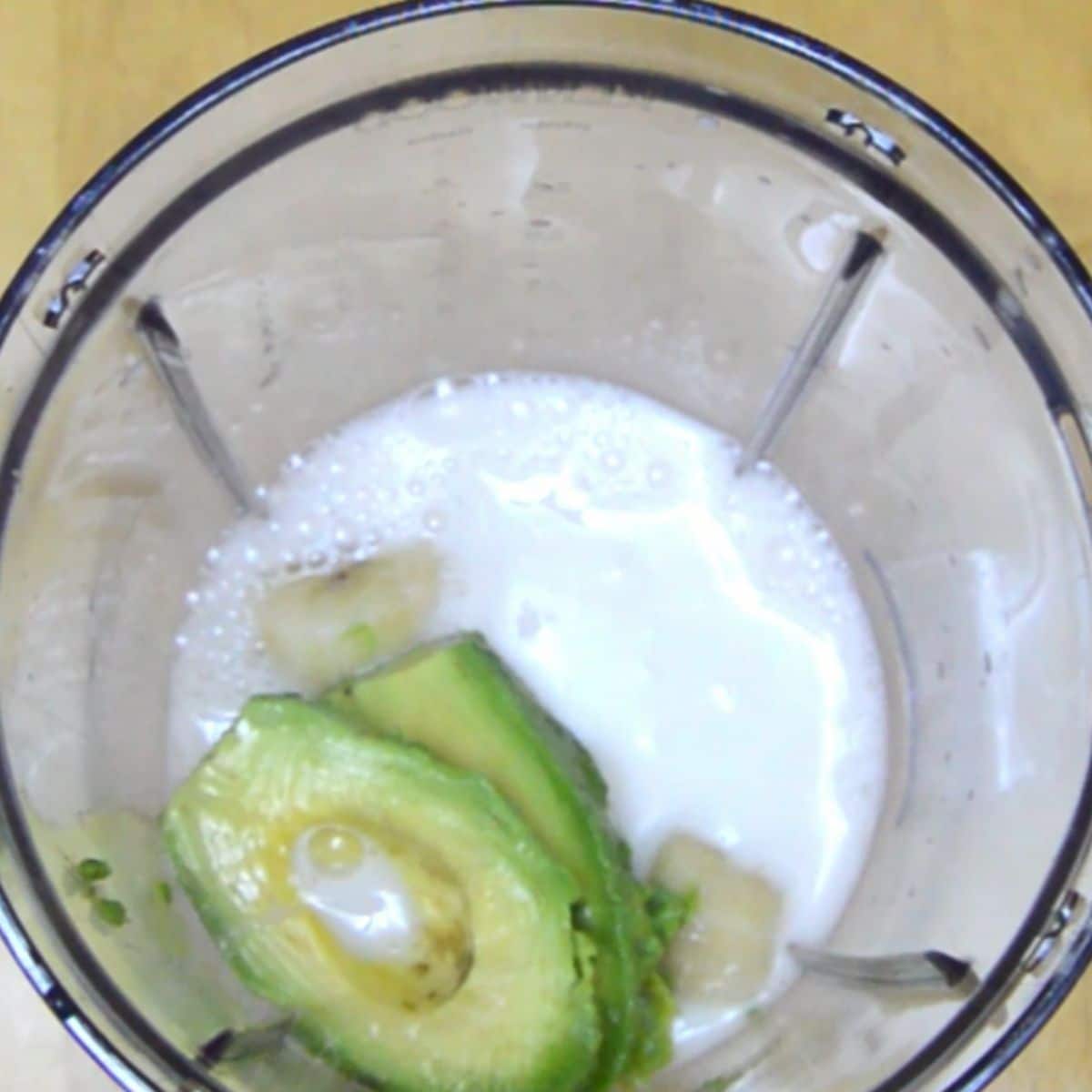avocado banana and milk in a blender jar.