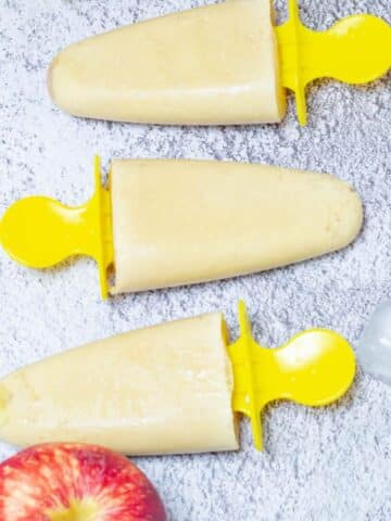 3 popsicles with apple and ice cubes placed on the tile.