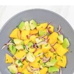 pin image of mango avocado salad with black text overlay on the top.