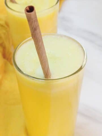 pineapple ginger juice in a glass with a straw on the marble.