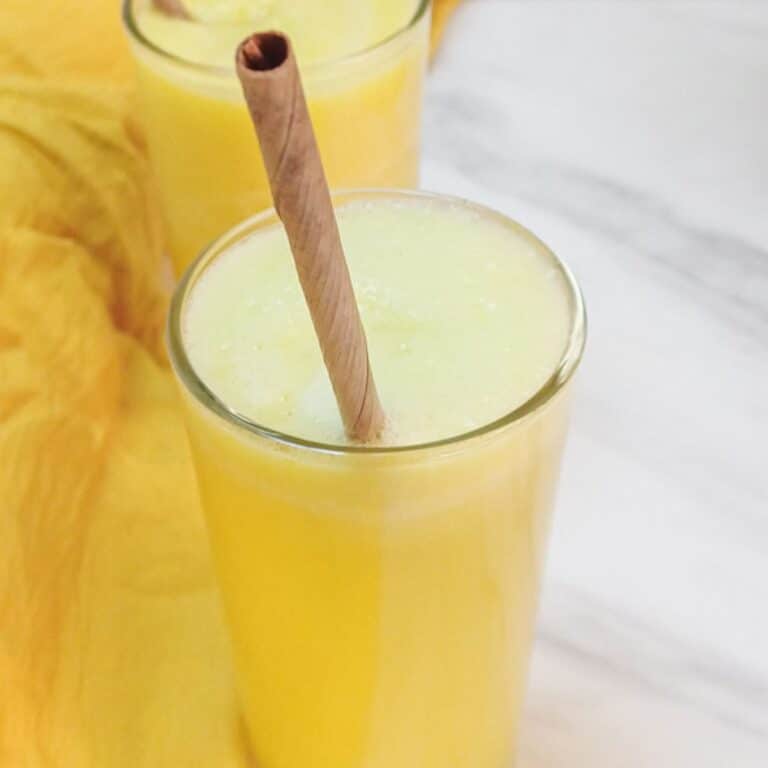pineapple ginger juice in a glass with a straw on the marble.